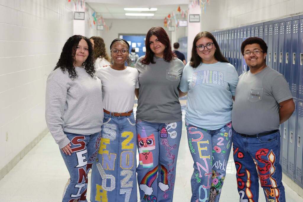 Five high school students with "Senior 2027" painted on their jeans