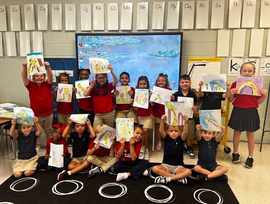 A group of students holding up drawings of giraffes