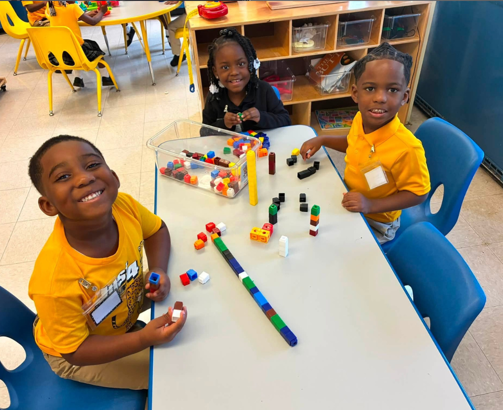 Three preschool students playing with colorful blocks on a table