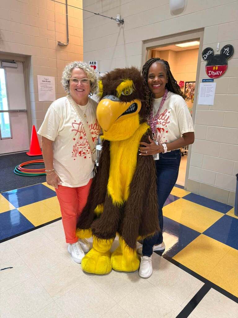 Dawes Intermediate's principal and assistant principal stand with the schools Hawk mascot