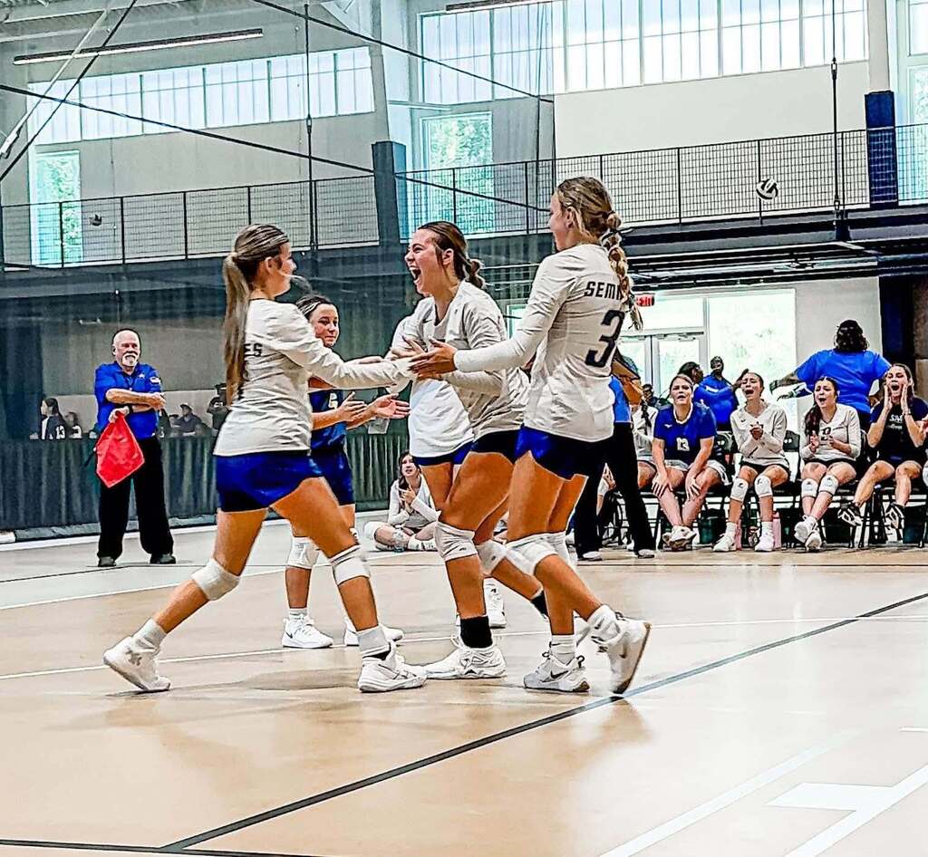 Three volleyball players congratulate each other on the court