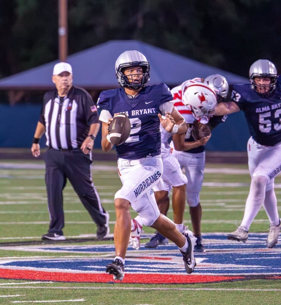 A quarterback in a blue jersey rolls out, looking to pass