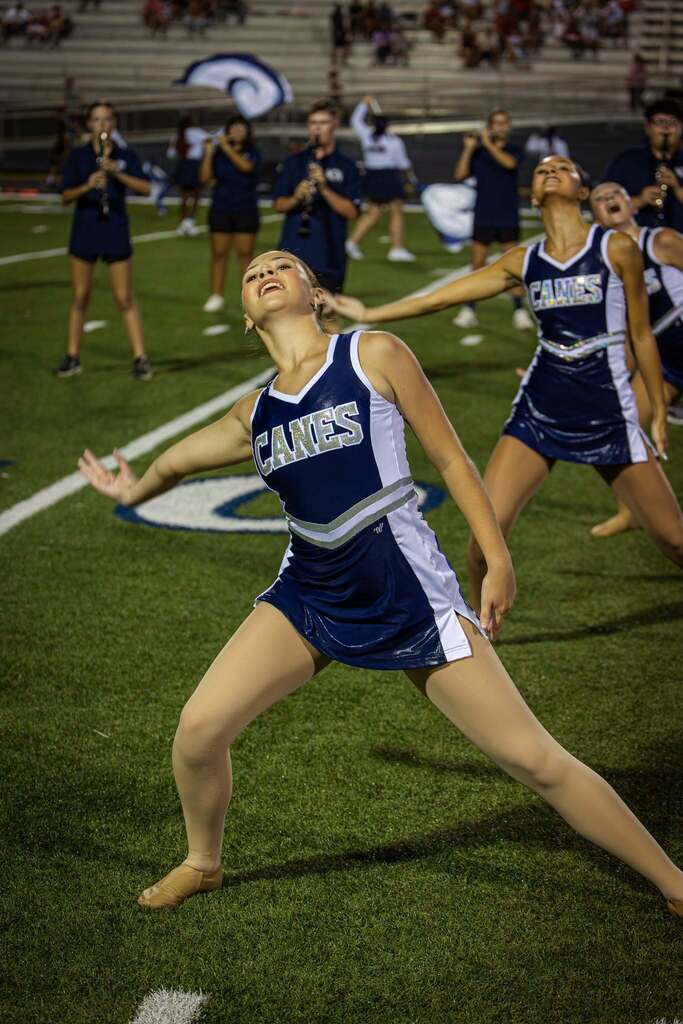 Dancers with "Canes" on their uniforms perform on a football field