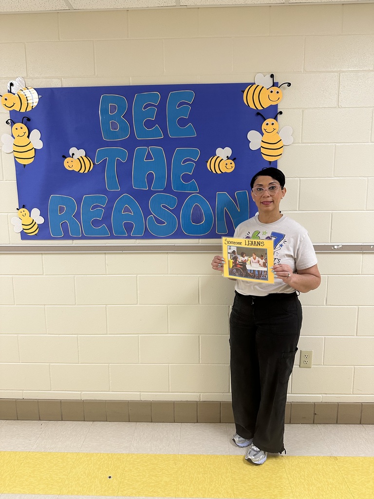 Be the reason someone learns, Mrs. Kidd standing in front of the "Bee the reason" Wall art with bumblebees