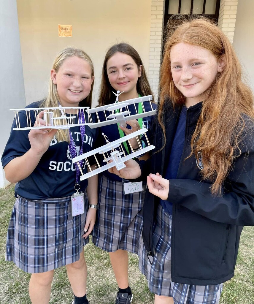 Three girls holding model airplanes