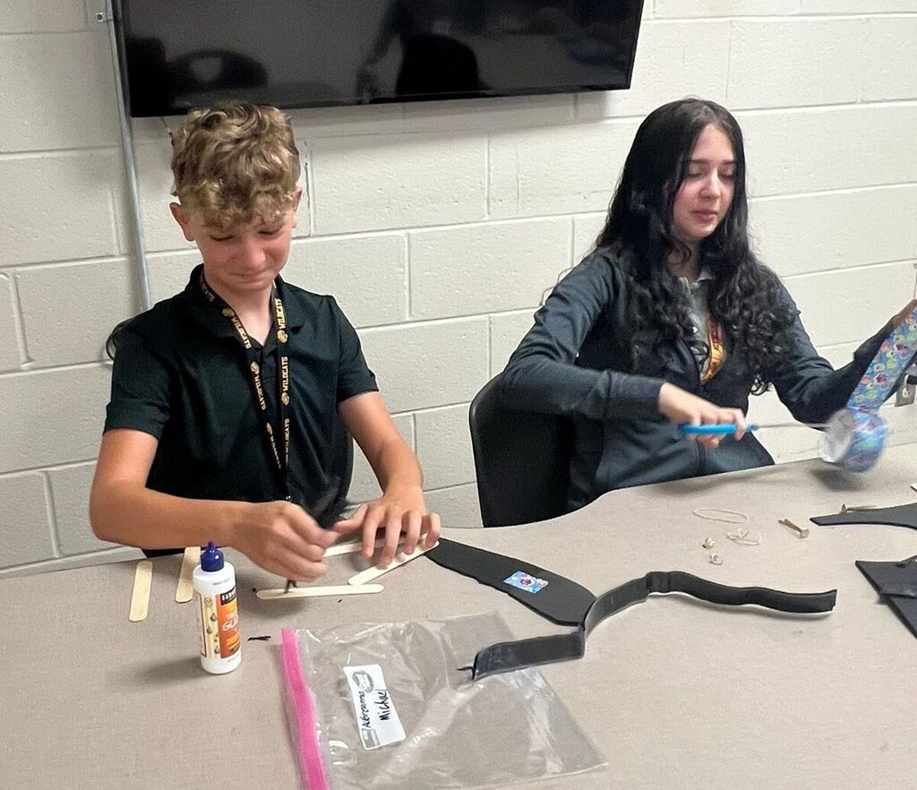 Two students working with popsicle sticks and glue at a table