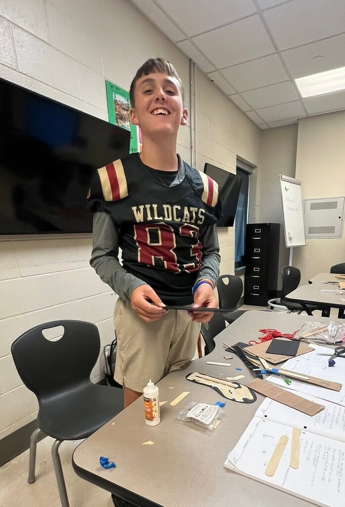 A boy in a football jersey holding a piece of cardboard