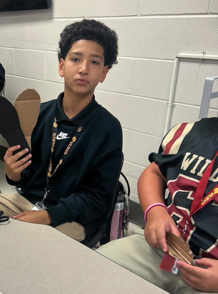 A boy holding two pieces of cardboard shaped like feet