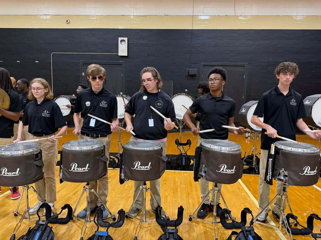 A drumline playing in a gymasium