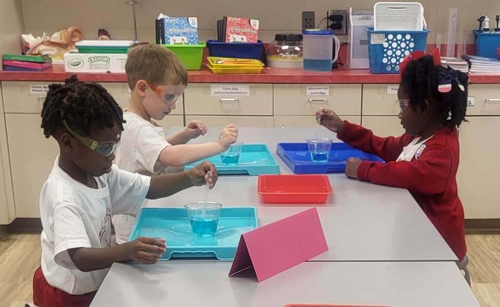 Students stirring blue liquid in cups