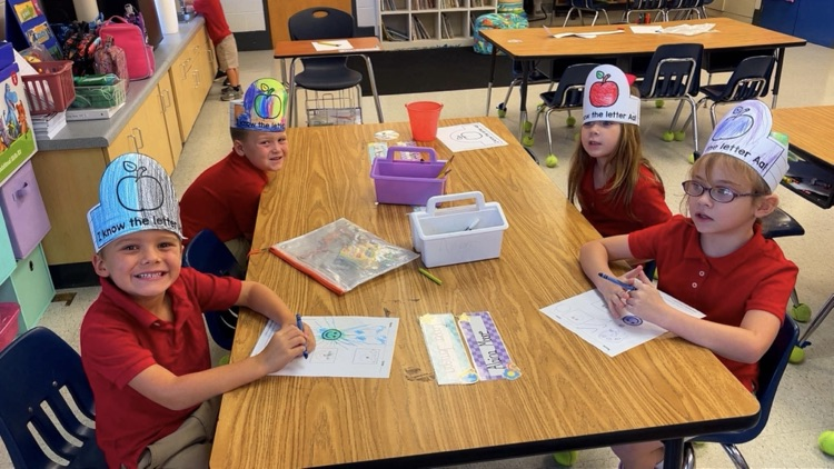 ms. richardson’s kindergarten students sitting at their tables working on the letter A. 