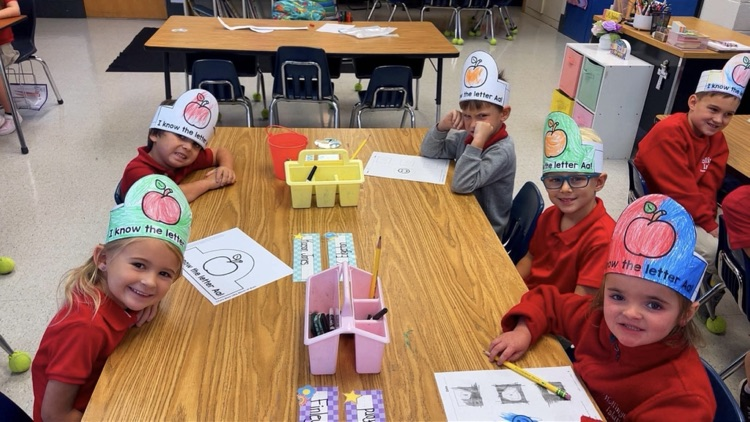 ms. richardson’s kindergarten students sitting at their tables working on the letter A. 