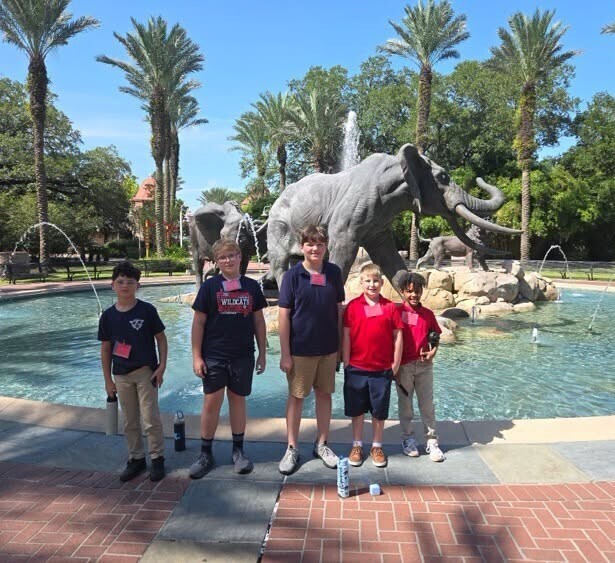 Five students standing in front of an elephant statue at a zoo