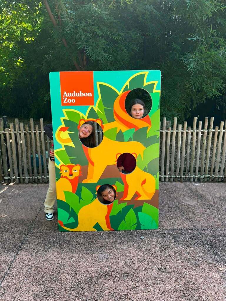 Three students sticking their head through a cutout at the Audubon Zoo