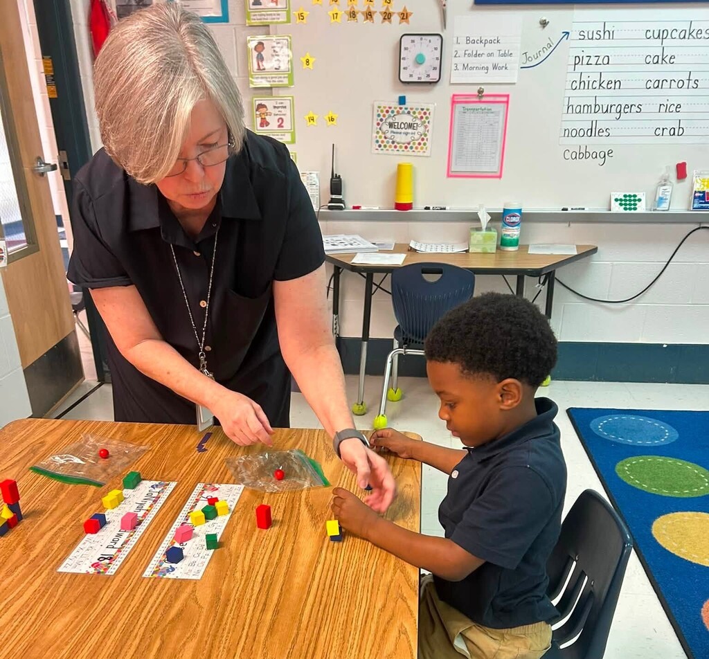 A teacher helping a boy sort math manipulatives