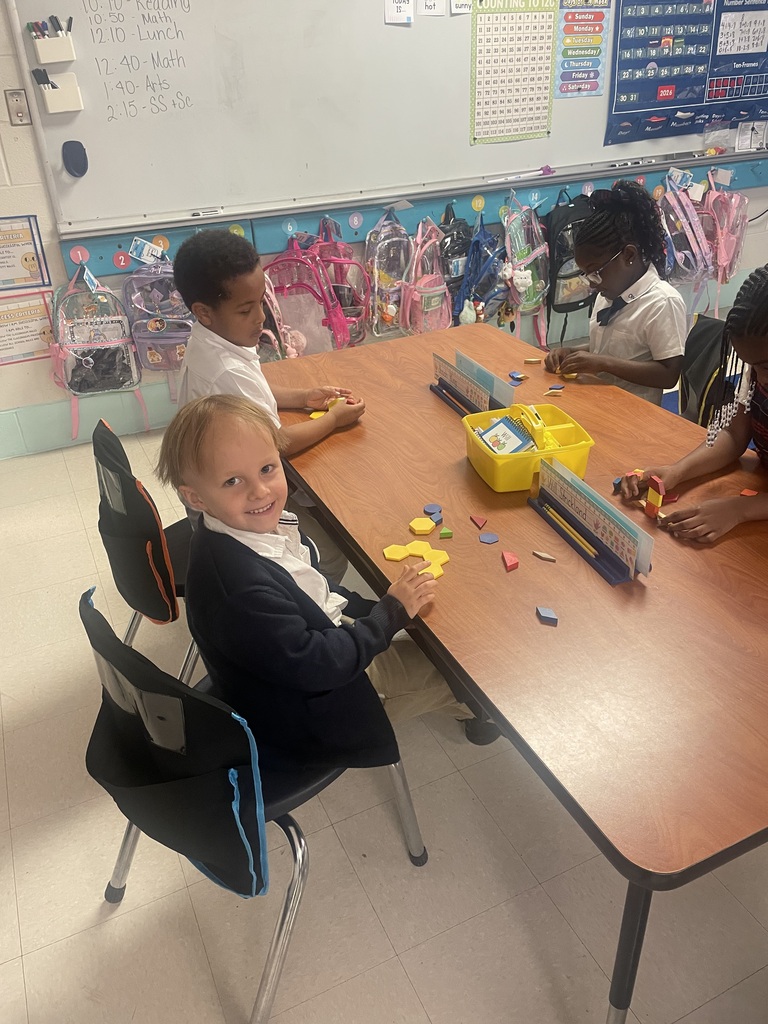 Students sorting shapes by their attributes while creating patterns.
