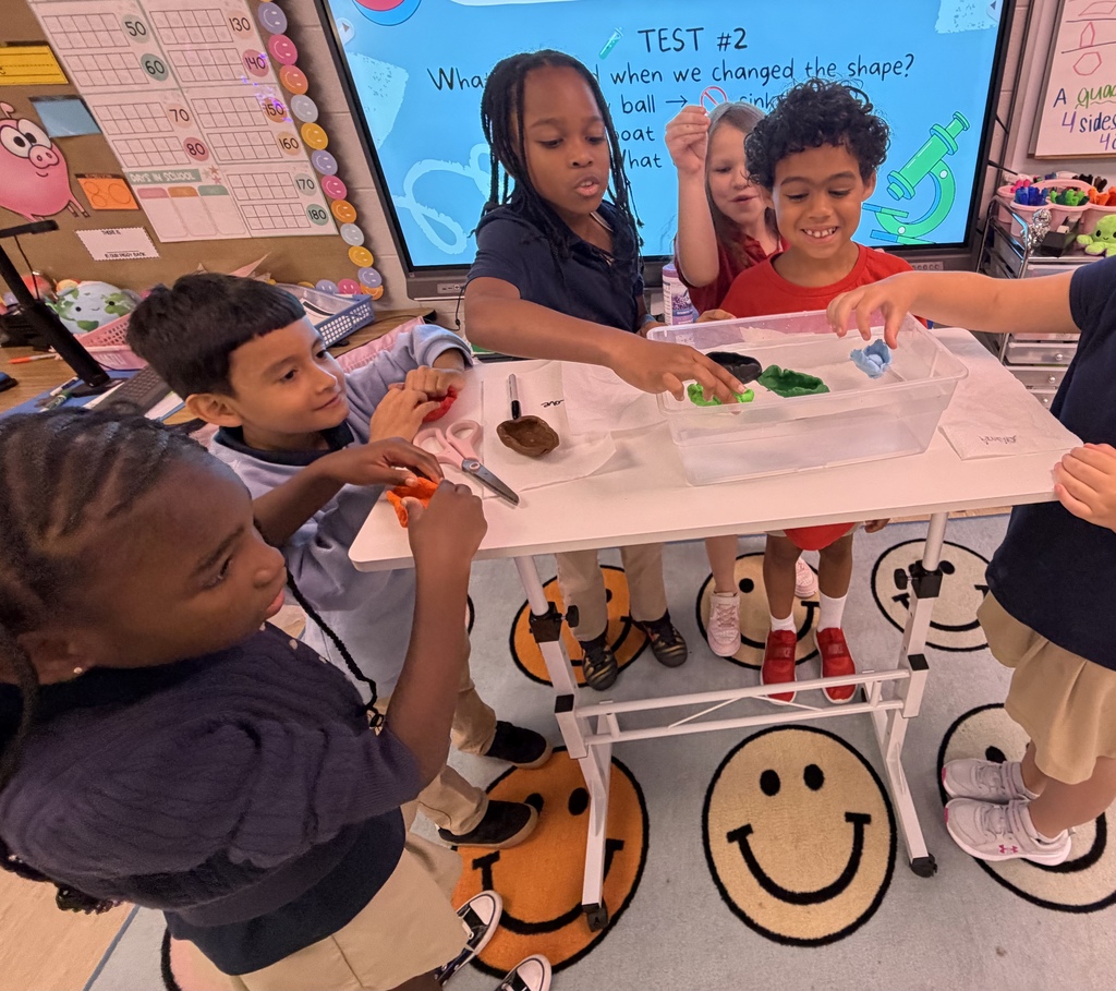 classroom of students dropping handmade boats into a bucket of water