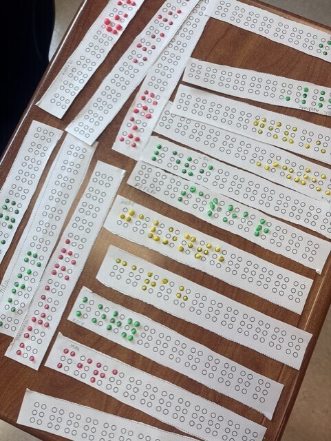 Multiple strips with colored dots in various positions on a brown surface. Dots are red, green, and yellow.