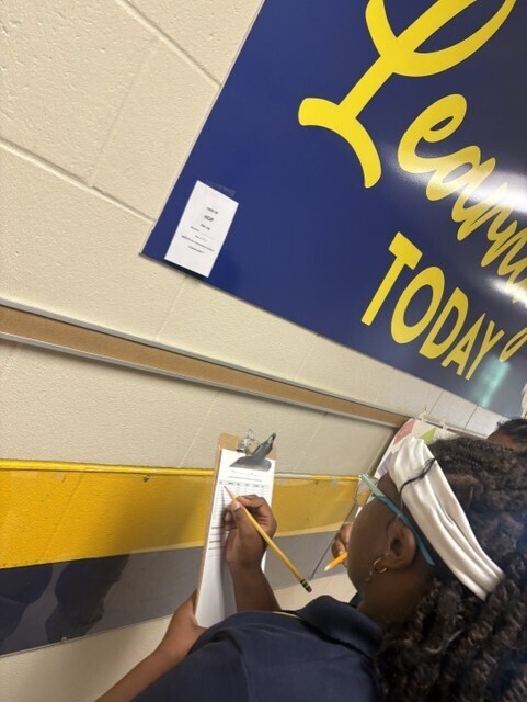 A person holds a paper and pencil, writing on a clipboard, with a yellow and blue banner reading "Learn Today" behind them.