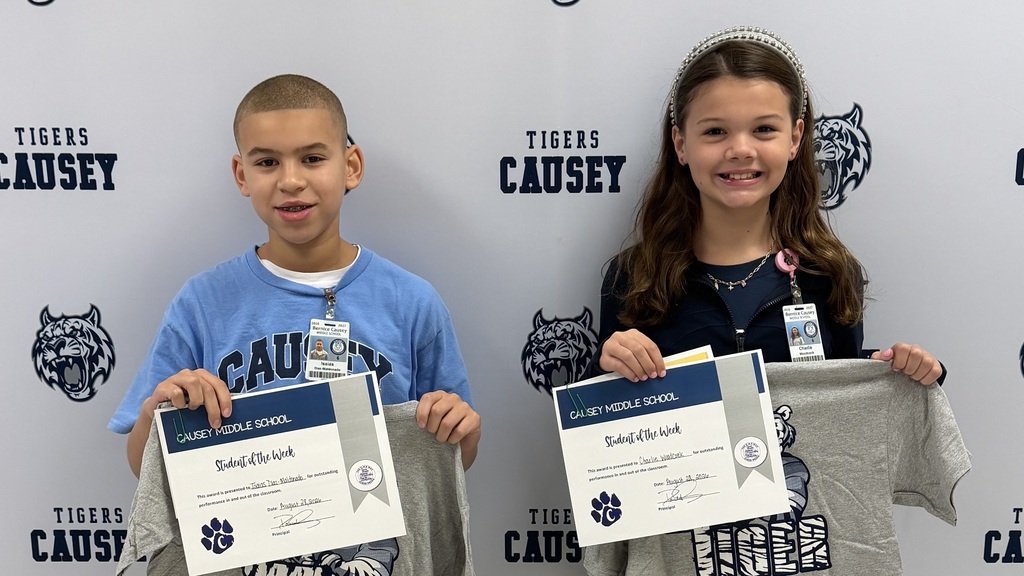 Two children holding certificates and t-shirts. One holds a certificate, the other a certificate and a t-shirt.
