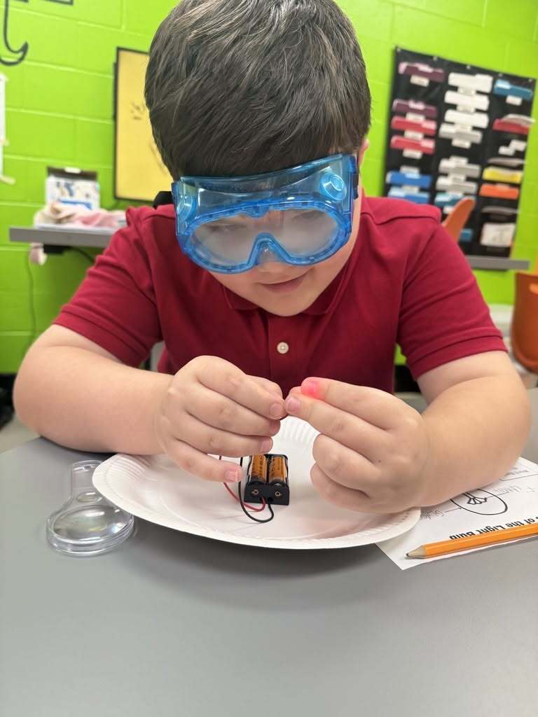 A boy in safety goggles working with a circuit