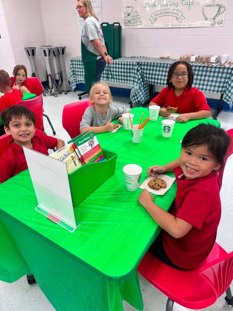 Four students eating cookies at a table