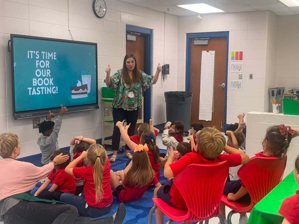 A teacher giving thumbs up in front of a room of students, who are also giving thumbs up