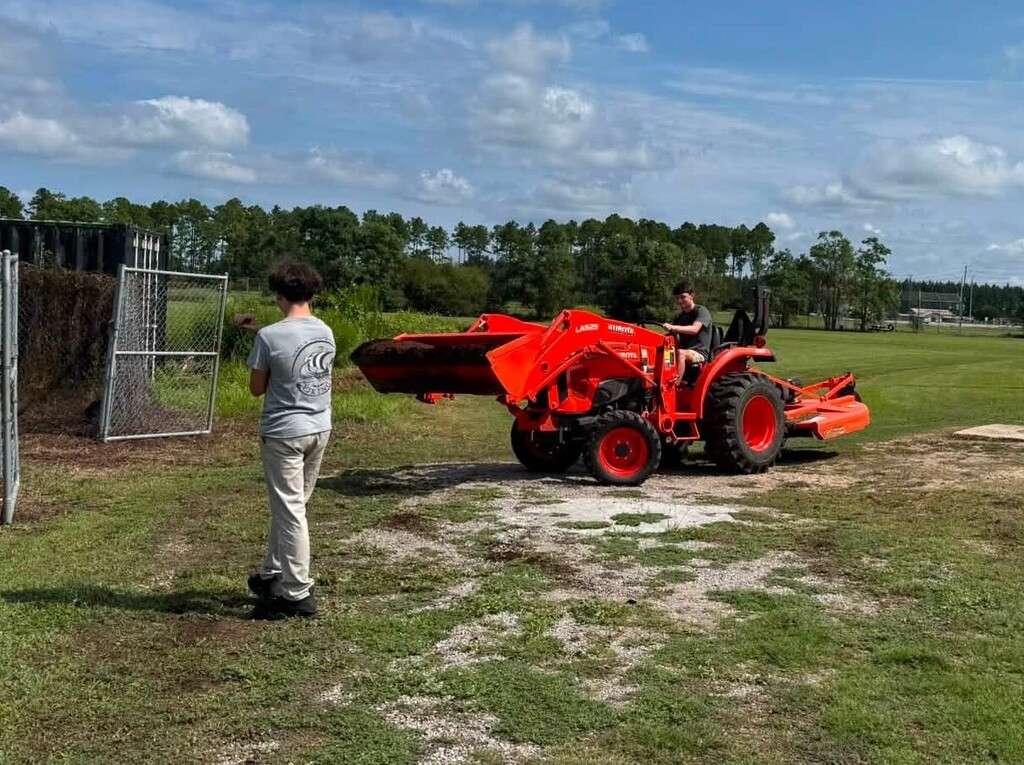 A boy drives a tractor while another watches