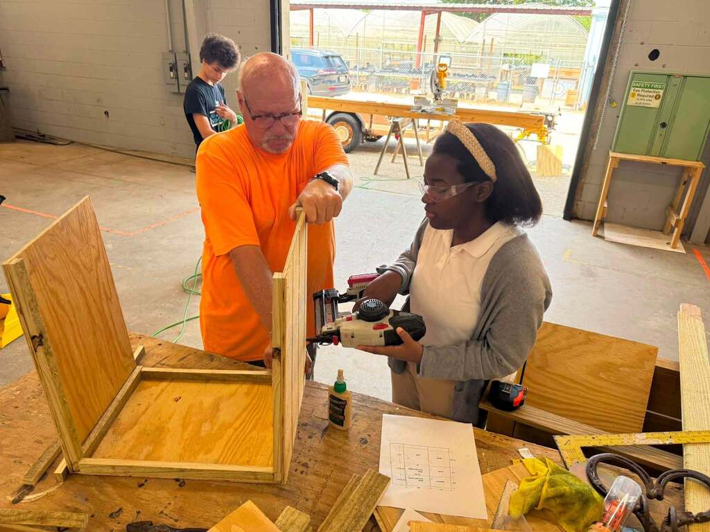A man and a student build a wooden box