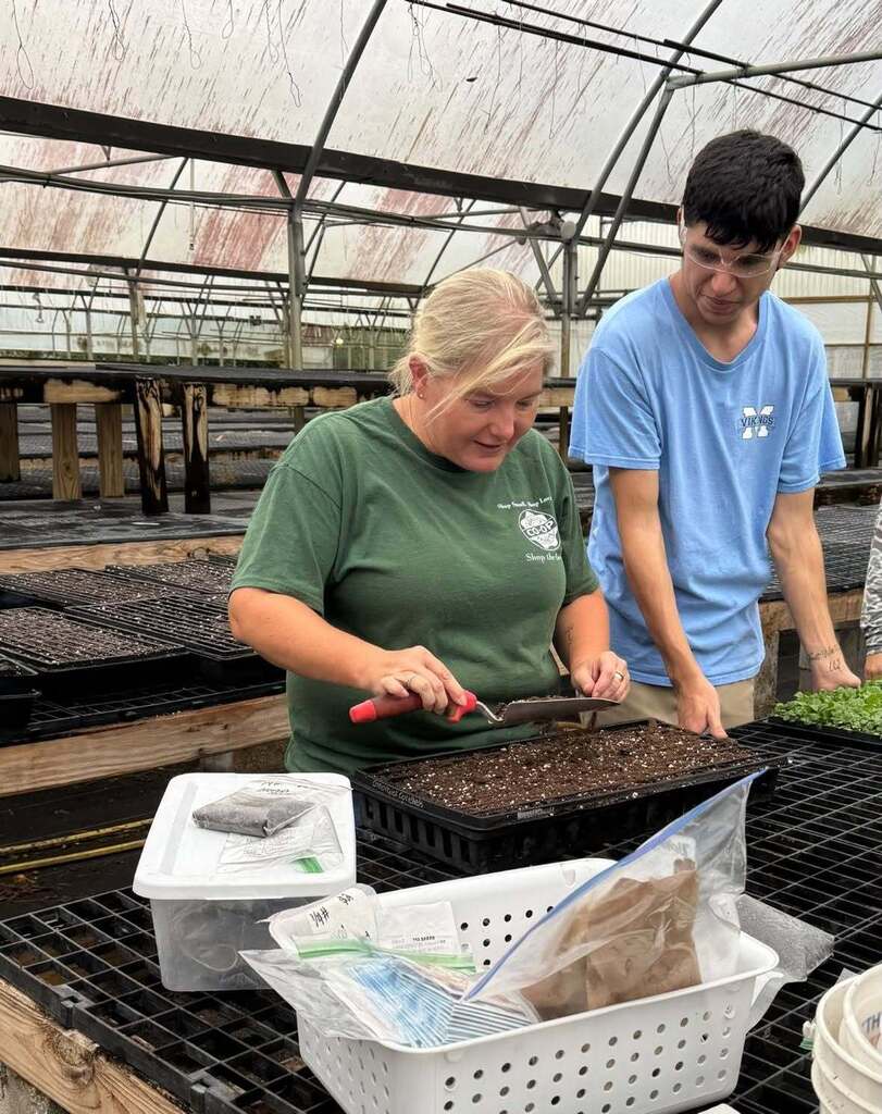 A teacher and student working with seedlings