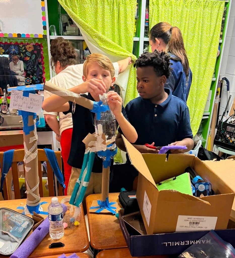 Two students working with a Rube Goldberg machine they made