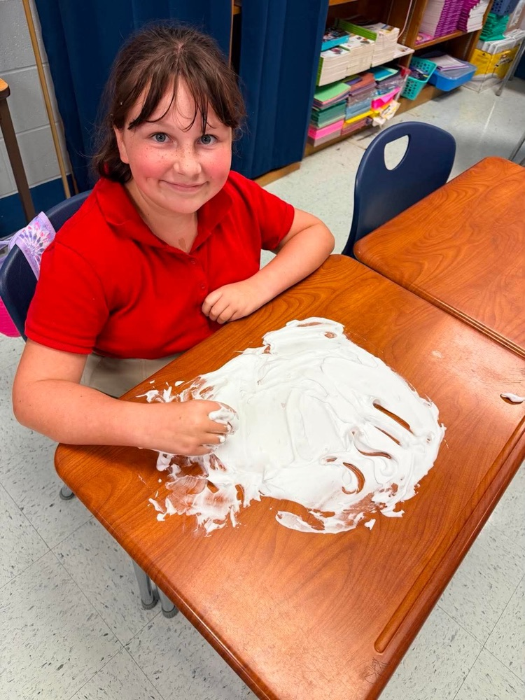 Mrs. Allen’s student writing spelling words in shaving cream on their desk in the classroom  