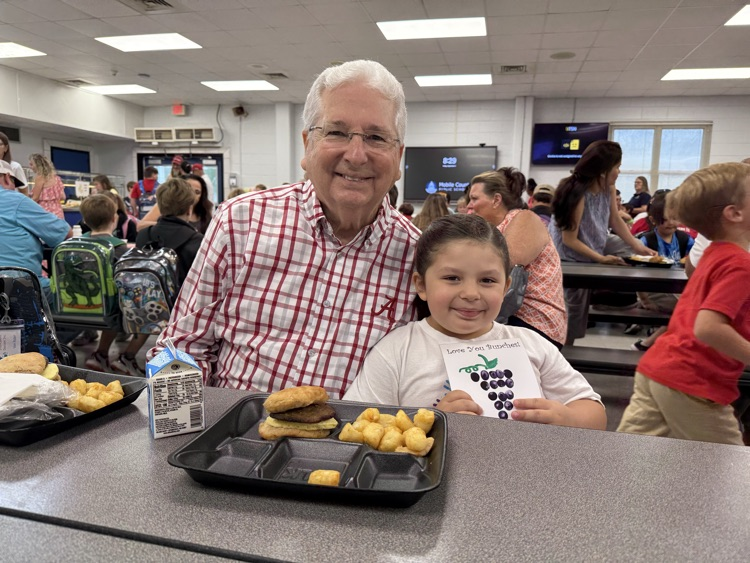 grandparents and students eating breakfast in the cafeteria in the school. 