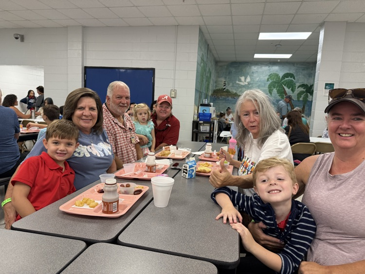grandparents and students eating breakfast in the cafeteria in the school. 