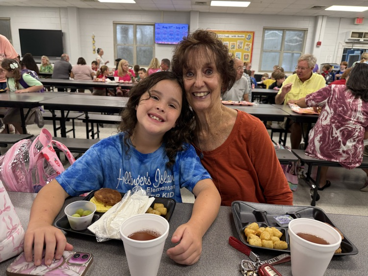 grandparents and students eating breakfast in the cafeteria in the school. 
