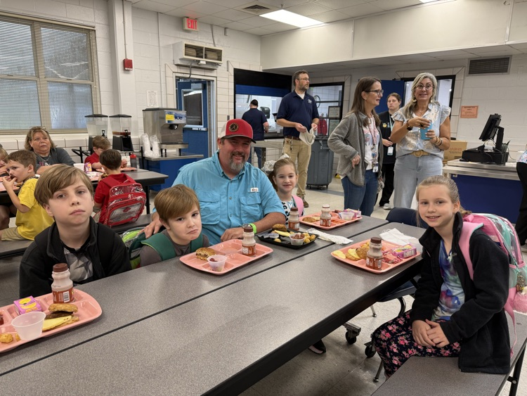 grandparents and students eating breakfast in the cafeteria in the school. 