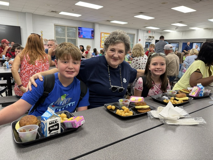 grandparents and students eating breakfast in the cafeteria in the school. 