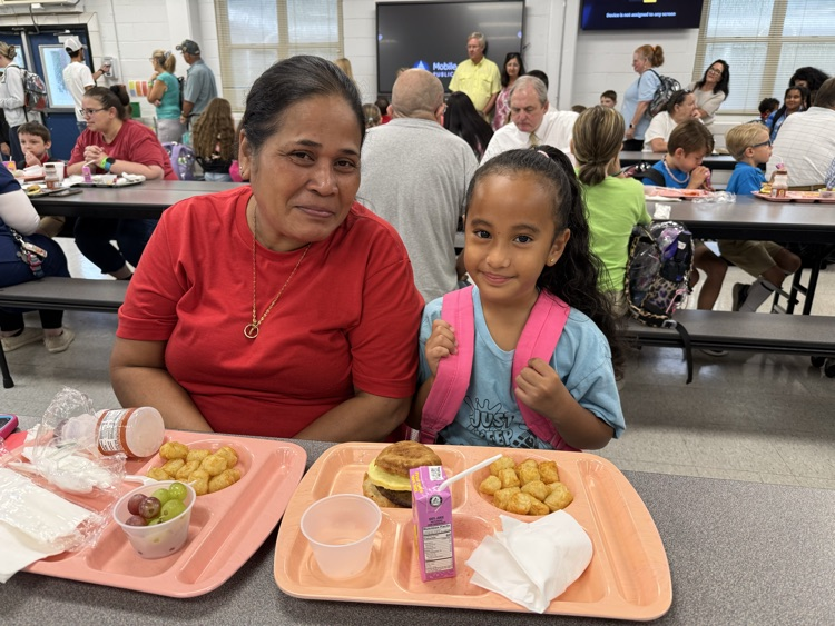 grandparents and students eating breakfast in the cafeteria in the school. 