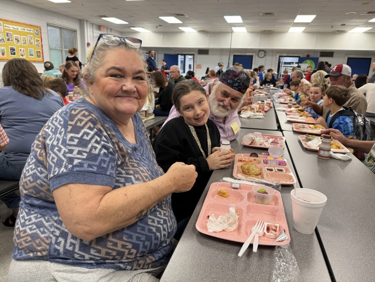 grandparents and students eating breakfast in the cafeteria in the school. 