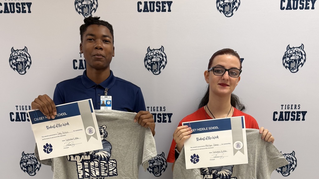 Two individuals in blue and red shirts hold certificates over a wall with the words "CAUSEY" and a tiger logo.