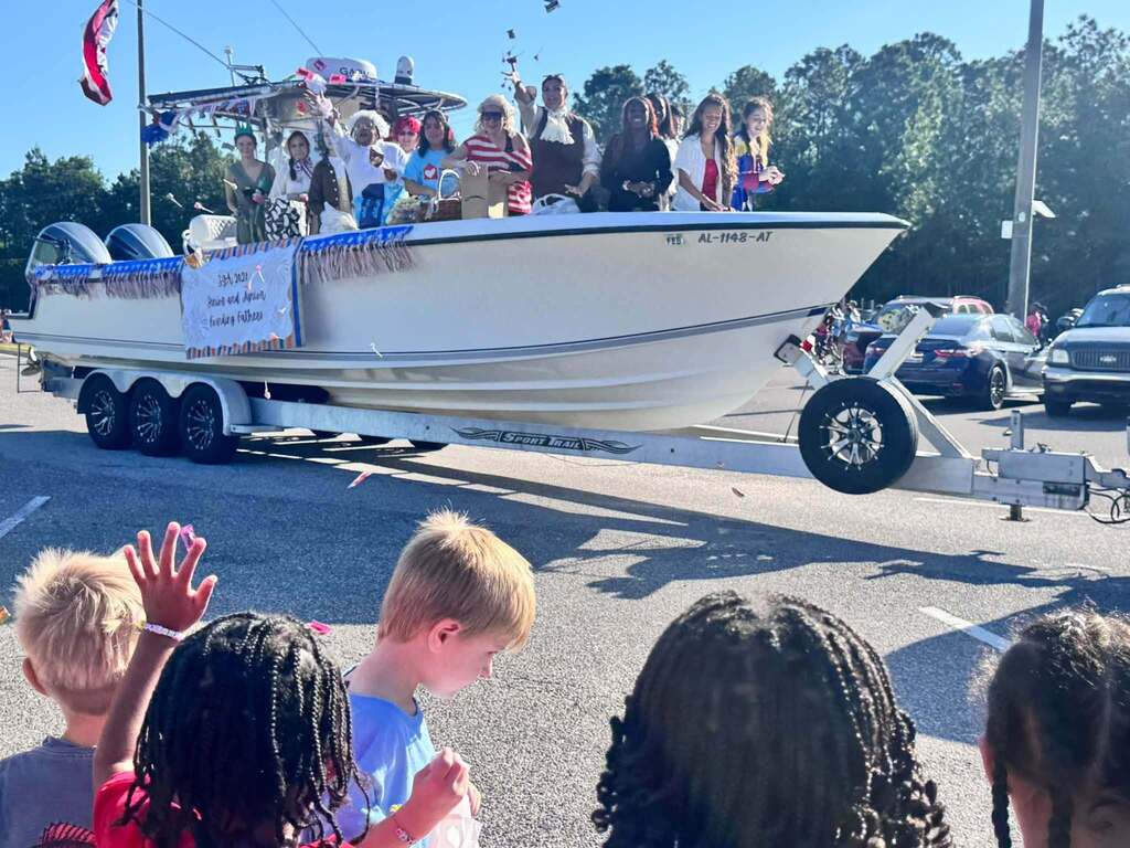 Student throwing trinkets off a boat being pulled on a trailer