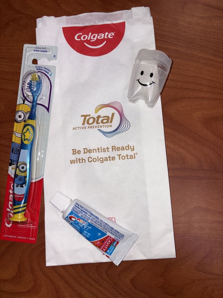 A bag with the words "Colgate Total" holds a toothbrush, a tube of toothpaste, and a tooth-shaped item.
