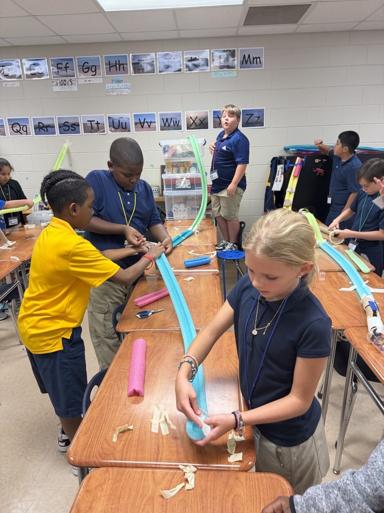 Students work on a project in a classroom. They use blue tubing on a table.