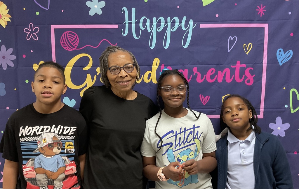 A woman and three children pose for a picture in front of a colorful backdrop.