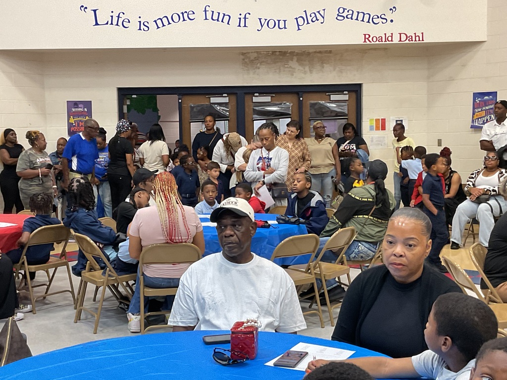 A room with tables and chairs where people gather. A quote reads "Life is more fun if you play games" above the entrance.
