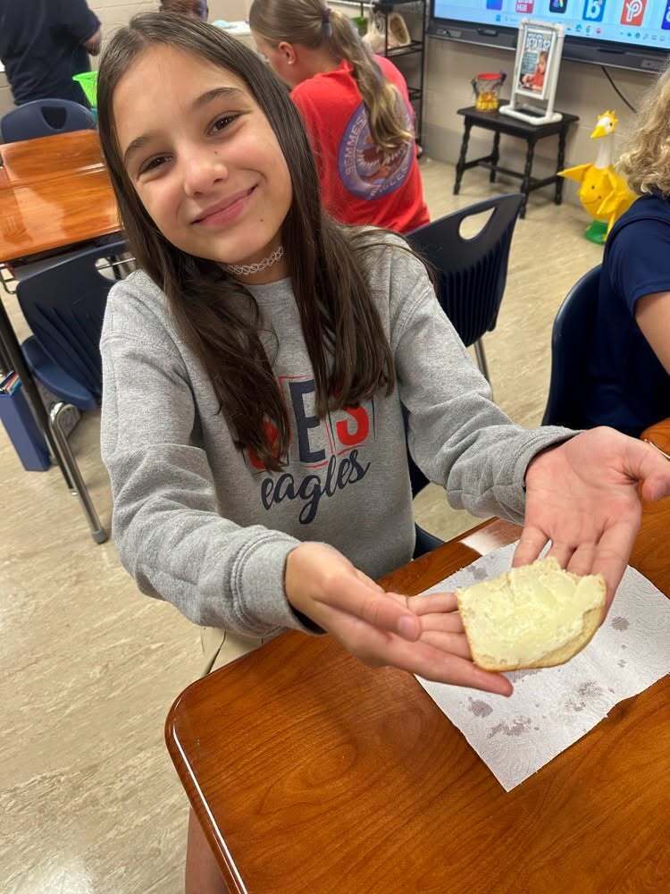 A girl holds a piece of buttered bread