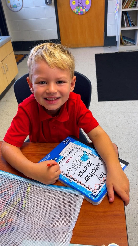 miss Richardson‘s kindergarten student holding or writing in their Weather journal in the classroom