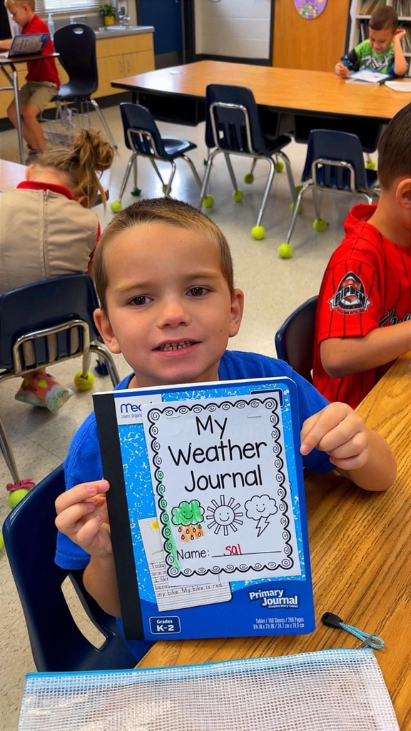 miss Richardson‘s kindergarten student holding or writing in their Weather journal in the classroom