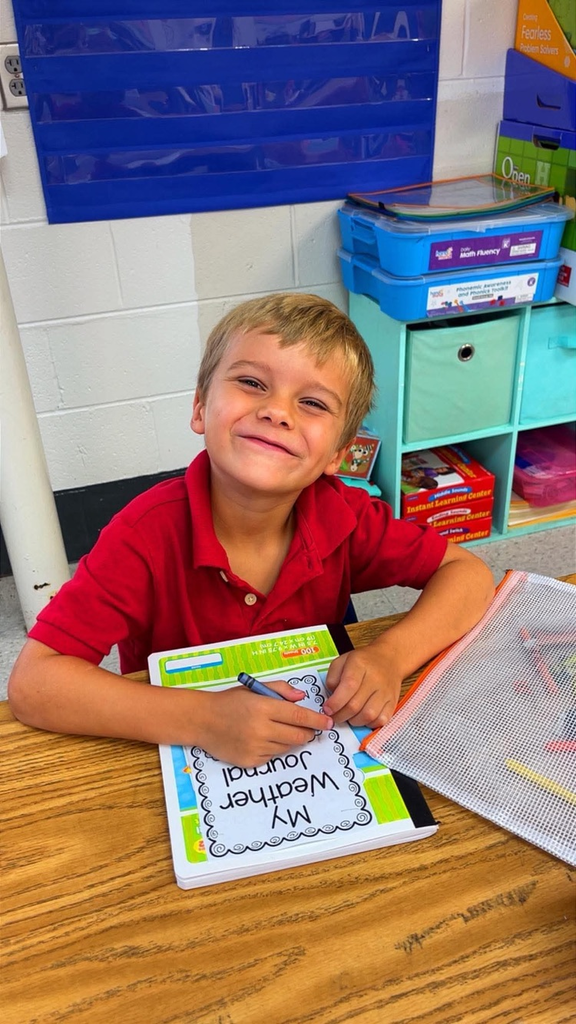 miss Richardson‘s kindergarten student holding or writing in their Weather journal in the classroom