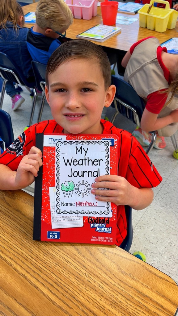 miss Richardson‘s kindergarten student holding or writing in their Weather journal in the classroom